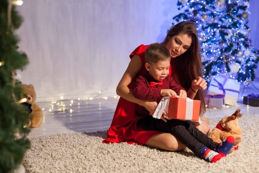 Mom and son on New Year's Eve at Christmas tree gifts lights garlands