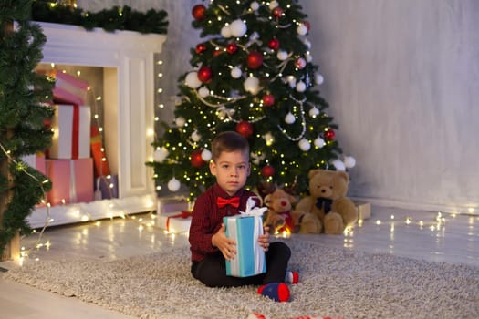 Little boy on New Year's Eve at the Christmas tree gifts lights