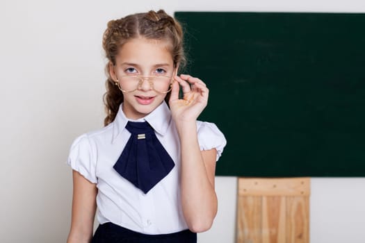 Schoolgirl stands at school board in classroom