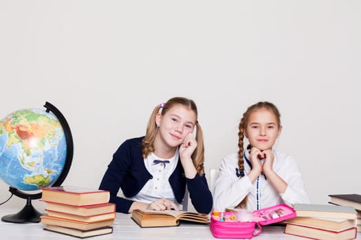 two girls with books and a globe in class at the desk