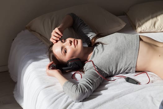 woman listens to music with headphones in the bedroom
