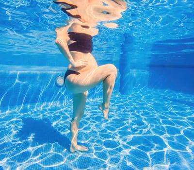 Embracing aquatic fitness, a pregnant woman demonstrates strength and serenity in underwater aerobics, creating a serene and empowering image in the pool.