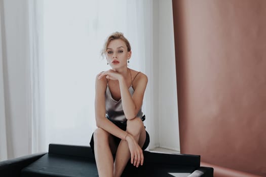 Portrait of a fashionable woman sits on a black office sofa