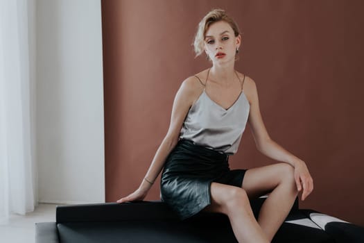 Portrait of a fashionable woman sits on a black office sofa