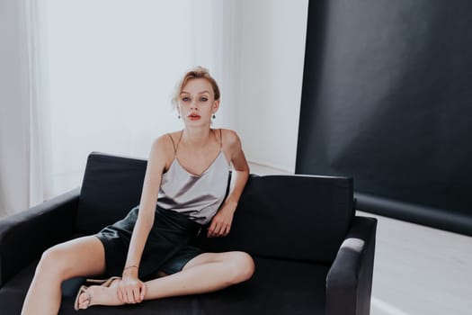 Portrait of a fashionable woman sits on a black office sofa