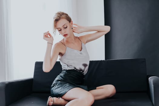 Portrait of a fashionable woman sits on a black office sofa