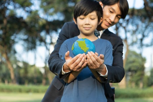 Asian boy and businessman holding planet Earth together as Earth day concept as corporate social responsible to make greener environmental protection for sustainable future generation. Gyre