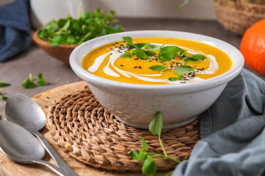 Delicious homemade creamy pumpkin soup with cream with sesame seeds and watercress.