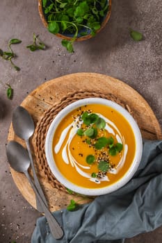 Delicious homemade creamy pumpkin soup with cream with sesame seeds and watercress.