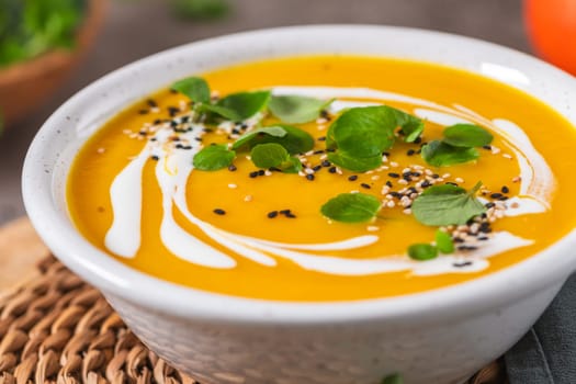 Delicious homemade creamy pumpkin soup with cream with sesame seeds and watercress.