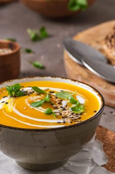 Delicious homemade creamy pumpkin soup with cream with sesame seeds and watercress.