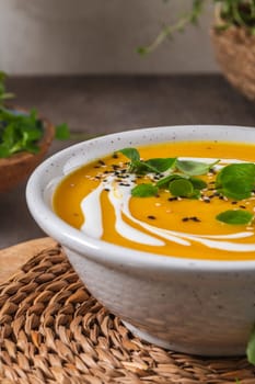 Delicious homemade creamy pumpkin soup with cream with sesame seeds and watercress.