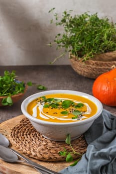 Delicious homemade creamy pumpkin soup with cream with sesame seeds and watercress.