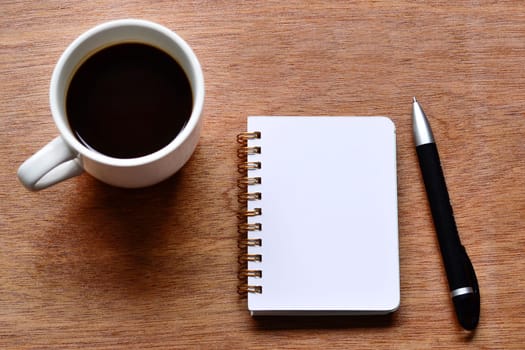 Directly above view of office desk with pen, notepad and coffee. Flat lay. Copy space.