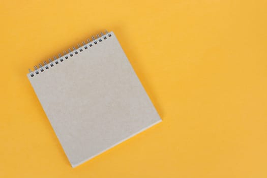 Top view of brown notepad on yellow background. Copy space. Flat lay.