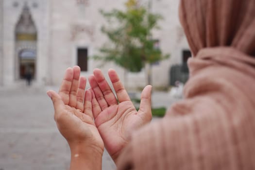 Muslim young woman in hijab is praying in mosque