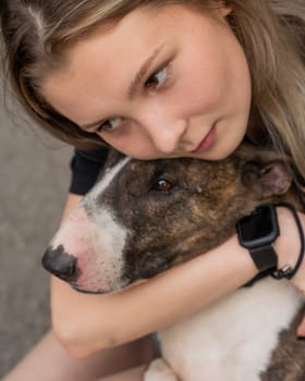 Portrait of caucasian woman hugging her bull terrier dog outdoors