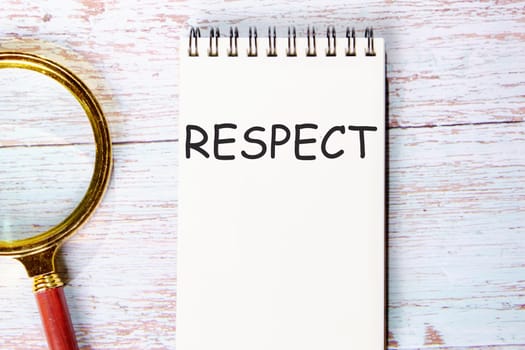 respect a word written on a notebook on wooden boards next to a magnifying glass