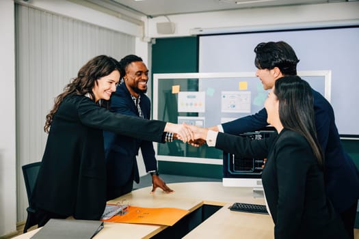Businessmen sealing a deal with a handshake in an office. Colleagues, including executives, lawyers, and managers, celebrate their successful partnership after a meeting. Teamwork