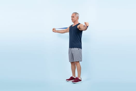 Full body length shot athletic and sporty senior man with fitness resistance band on isolated background. Healthy active physique and body care lifestyle after retirement. Clout