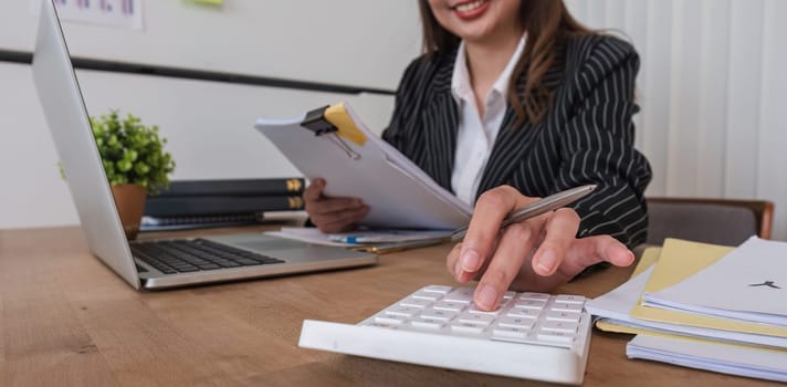 Young Asian business woman presses a calculator to calculate information about expenses..