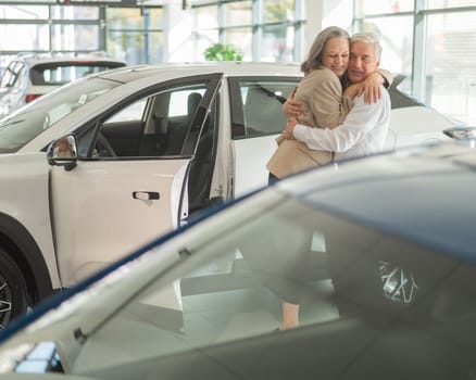 Mature Caucasian couple hugging. Elderly man and woman buying a new car