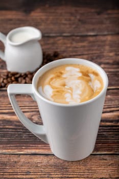 Relaxing latte coffee in white porcelain cup on wooden table