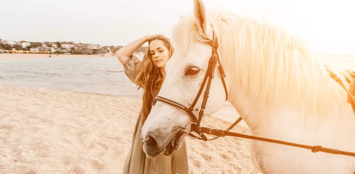 A woman in a dress stands next to a white horse on a beach, with the blue sky and sea in the background