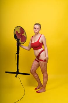 Professional fashion model blonde woman posing sitting in a red lingerie with big fan