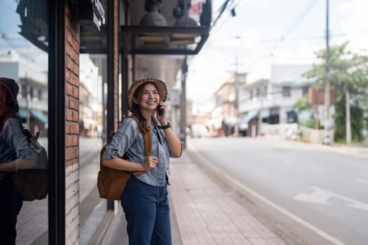 Happy young Asian tourist woman using smartphone on street with market background, Female traveller enjoy shopping market during holidays.