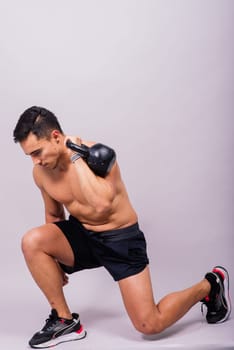 Handsome muscular man holding a kettle bell with copy space. Hispanic male athlete