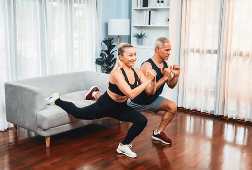 Active and fit senior couple warmup and stretching using furniture before home exercising routine at living room. Healthy fitness lifestyle concept after retirement for pensioner. Clout