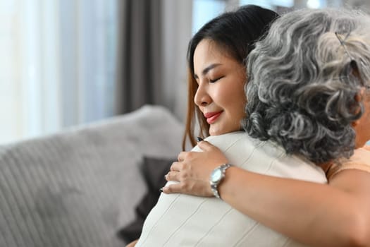 Loving Asian adult daughter hugging happy mature mother. International hug day concept.