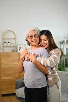 Loving Asian adult daughter hugging happy mature mother. International hug day concept.