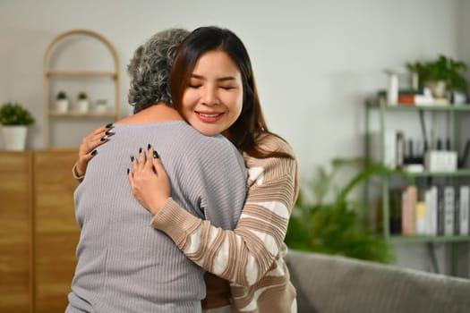 Affectionate young woman hugging senior mother expressing unconditional love.