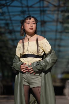 A beautiful Asian woman in shorts and a green leather coat comes out of the subway