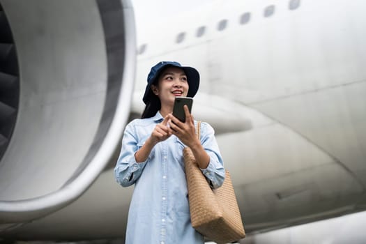 Pretty young woman asian using smartphone waiting for boarding in airport terminal. Travel and technology.