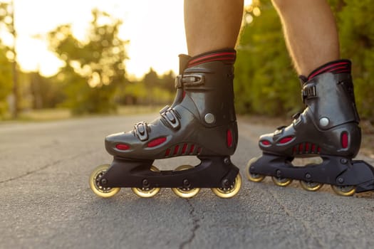 unrecognizable feet with rolling skate close up on rural paved street with sun flare or back light low angle view.