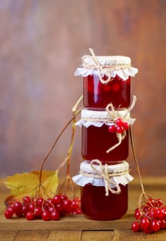 viburnum jam. Red juicy berries of a viburnum with sugar in a glass jar on a dark wooden background. For making jam, tea.