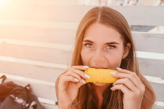 Healthy vegetarian hipster woman in summer outfit eat grilled corn and look to camera. Sexy lady on sea beach sunset or ocean sunrise. Travel, explore, active yoga and meditation lifestyle concept.