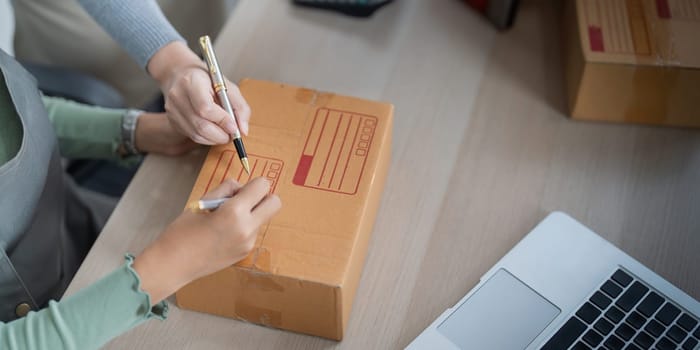 Startup small business owner working with computer at workplace. Two woman seller check product order. Packing goods for delivery to customer. Online selling. Ecommerce. Online Shopping.