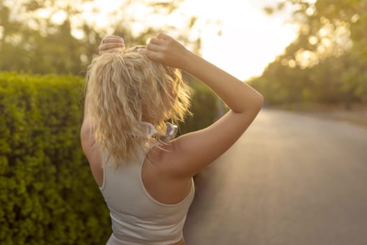 Portrait of fit girl preparing for running in workout clothes looking at camera smiling. Beautiful happy sportswoman enjoying doing sports listening to music using headphones. Music concept