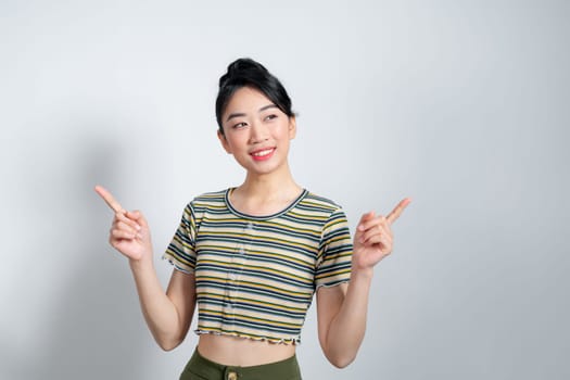 Happy Asian woman presenting or pointing fingers with copy space for product isolated on white background