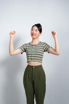 Beautiful Asian woman raises arms and fists clenched with shows strong powerful,