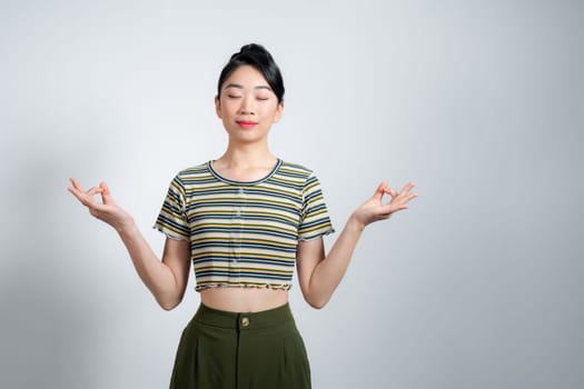 Portrait of calm beautiful woman holding hands up in mudra gesture, keeping eyes closed while meditating, yoga practice,