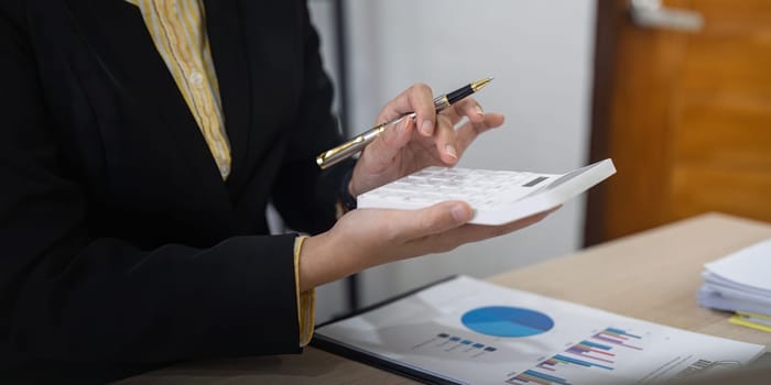 Businesswoman accountant using calculator and laptop for financial data saving in office room, Business financial, tax, accounting concept.