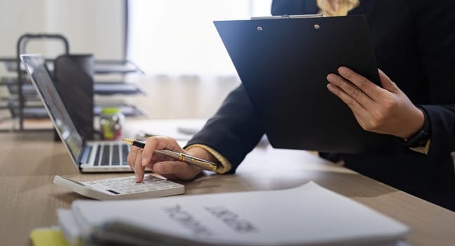 Businesswoman accountant using calculator and laptop for financial data saving in office room, Business financial, tax, accounting concept.