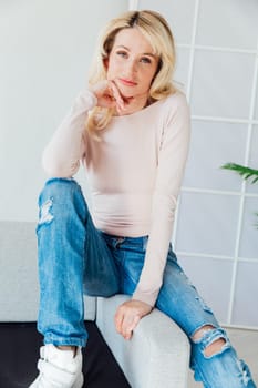 Beautiful blonde woman in jeans at home