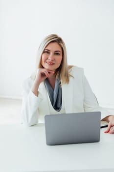 works online on a laptop computer, prints text to a project partner. The student manager is sitting on a chair of a young woman of Caucasian appearance. a favorite work, a comfortable business suit