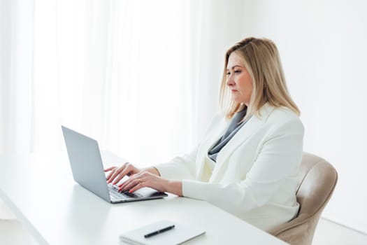 works online on a laptop computer, prints text to a project partner. The student manager is sitting on a chair of a young woman of Caucasian appearance. a favorite work, a comfortable business suit